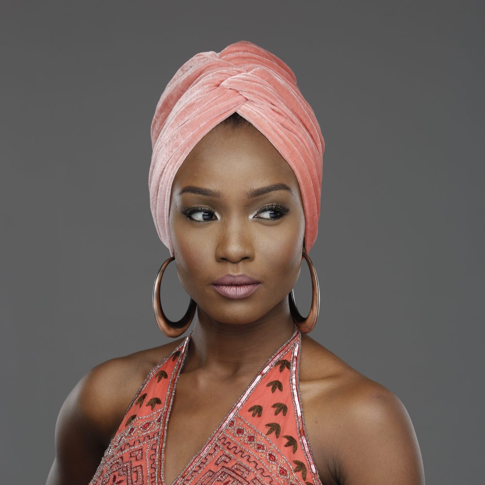 Model wearing a coral velvet headwrap and beaded halter top